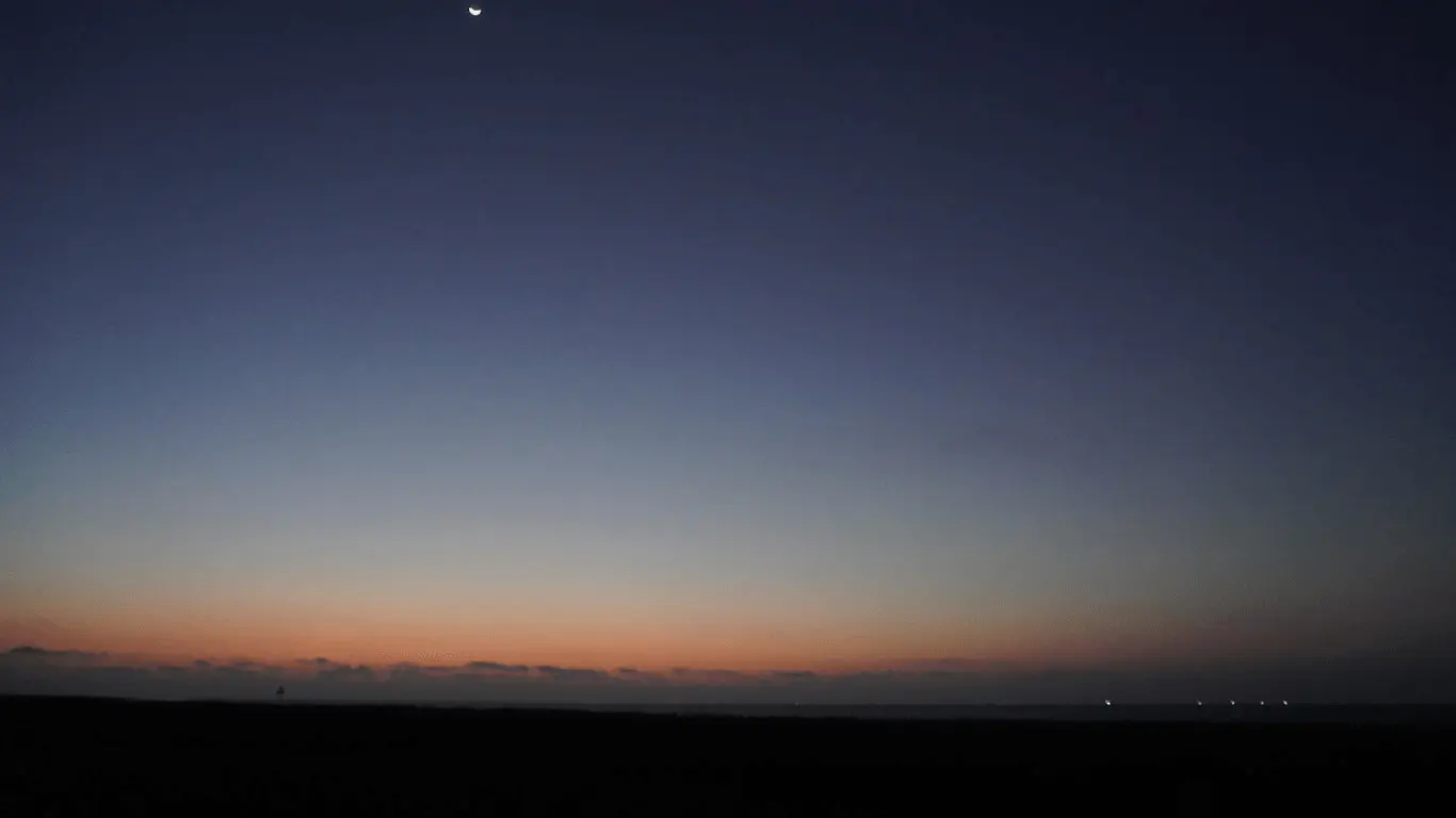 A thin crescent Moon and the bright point of Venus in the last colours of twilight.