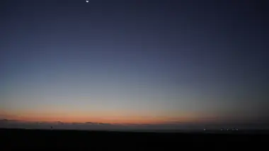 Un fin croissant de Lune et le point brillant de Vénus dans les dernières couleurs du crépuscule.
