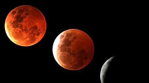 Composite photographique de plusieurs phases d'une éclipse de Lune : deux disques entièrement cuivrés par l'ombre de la Terre, puis un croissant gris resté éclairé par le Soleil.