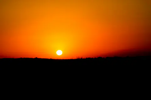 Un coucher de Soleil doré sur un horizon dégagé : à l'équinoxe, et seulement là, il se couche plein ouest.